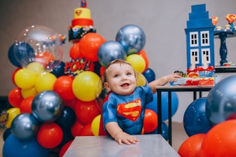 a baby sitting at a table surrounded by balloons
