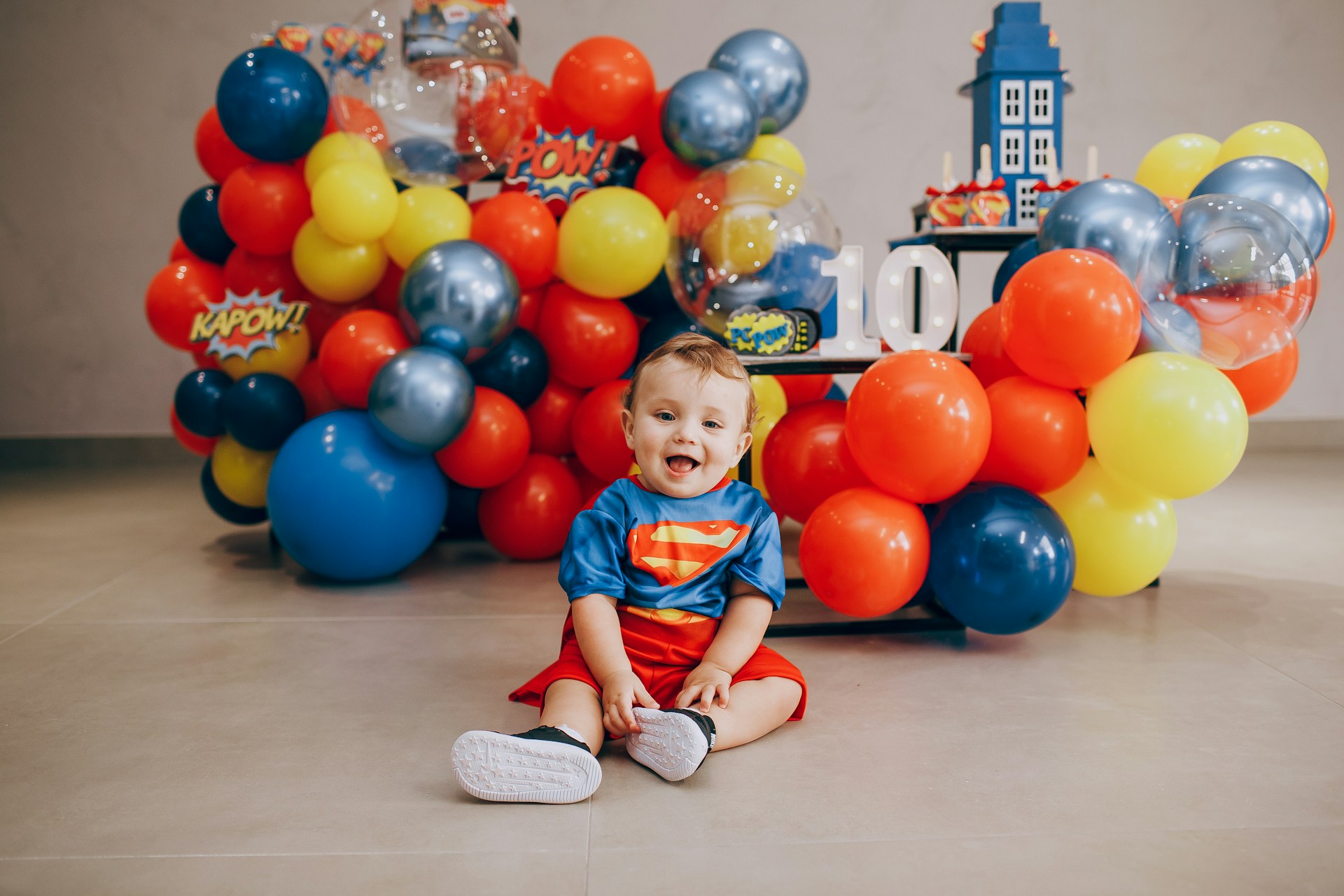 a little boy sitting in front of a bunch of balloons