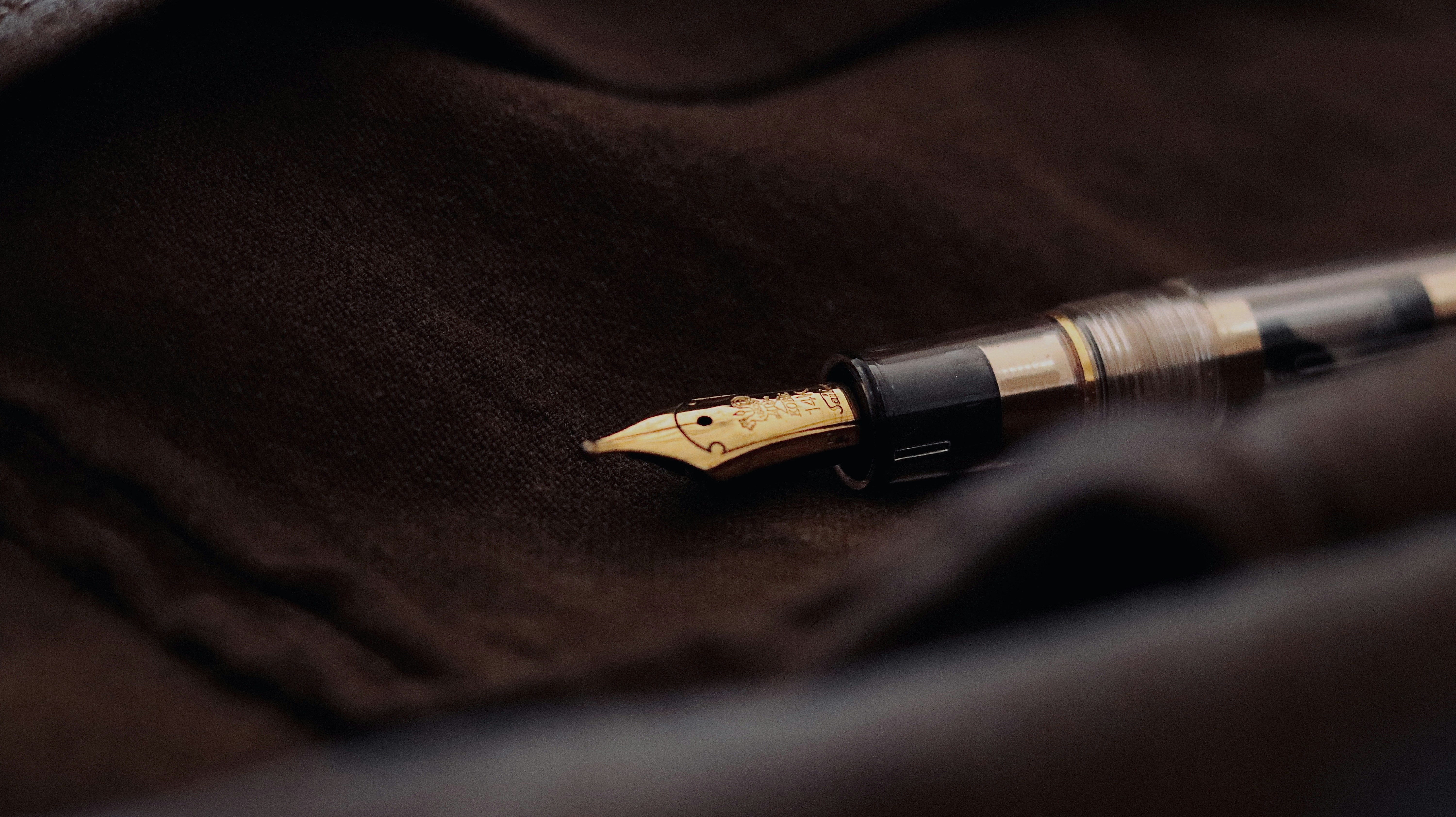 a fountain pen laying on a brown cloth, 