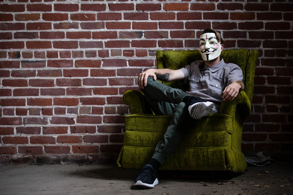 a man in a clown mask sitting on a green chair