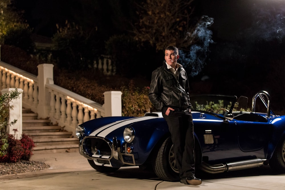 a man standing next to a blue sports car