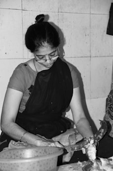 A village woman happily operating a small food processing machine inside a modest rural home.