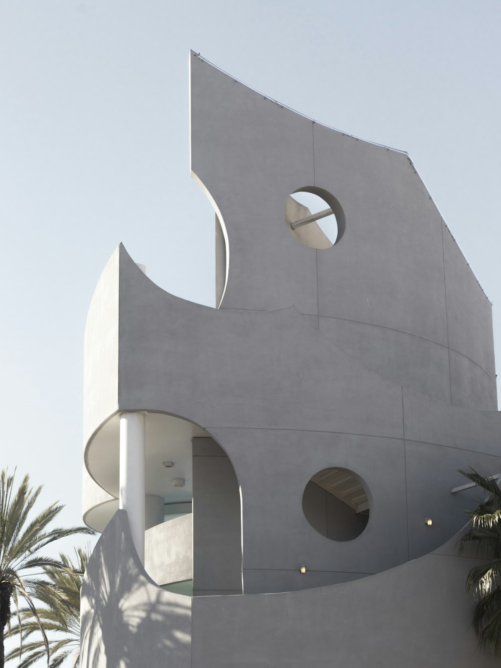 a white building with a circular window and a palm tree