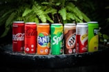 An assortment of fizzy drinks lined up on a rustic wooden surface under warm lighting