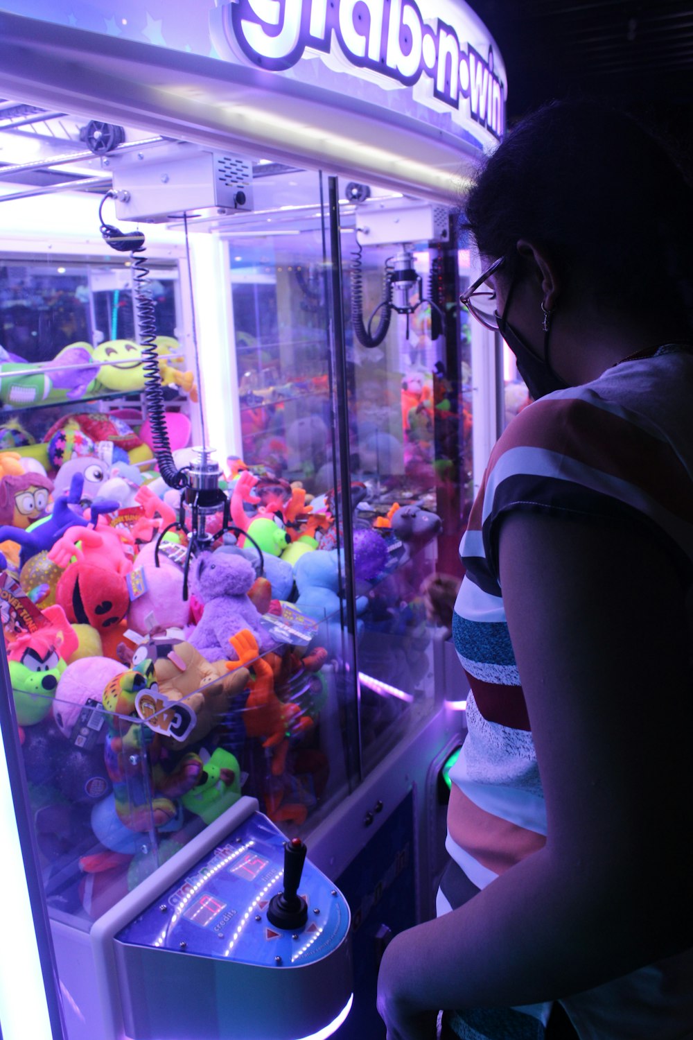 a woman standing in front of a vending machine filled with stuffed animals