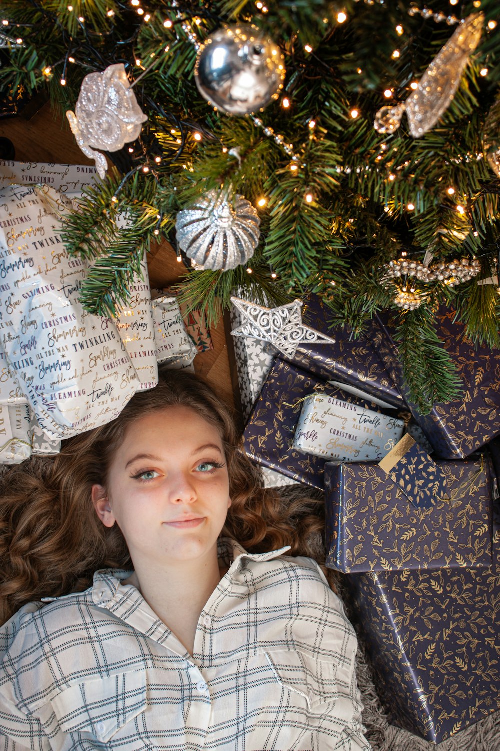 a young girl laying under a christmas tree