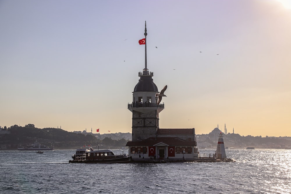 a lighthouse with a flag on top of it in the water