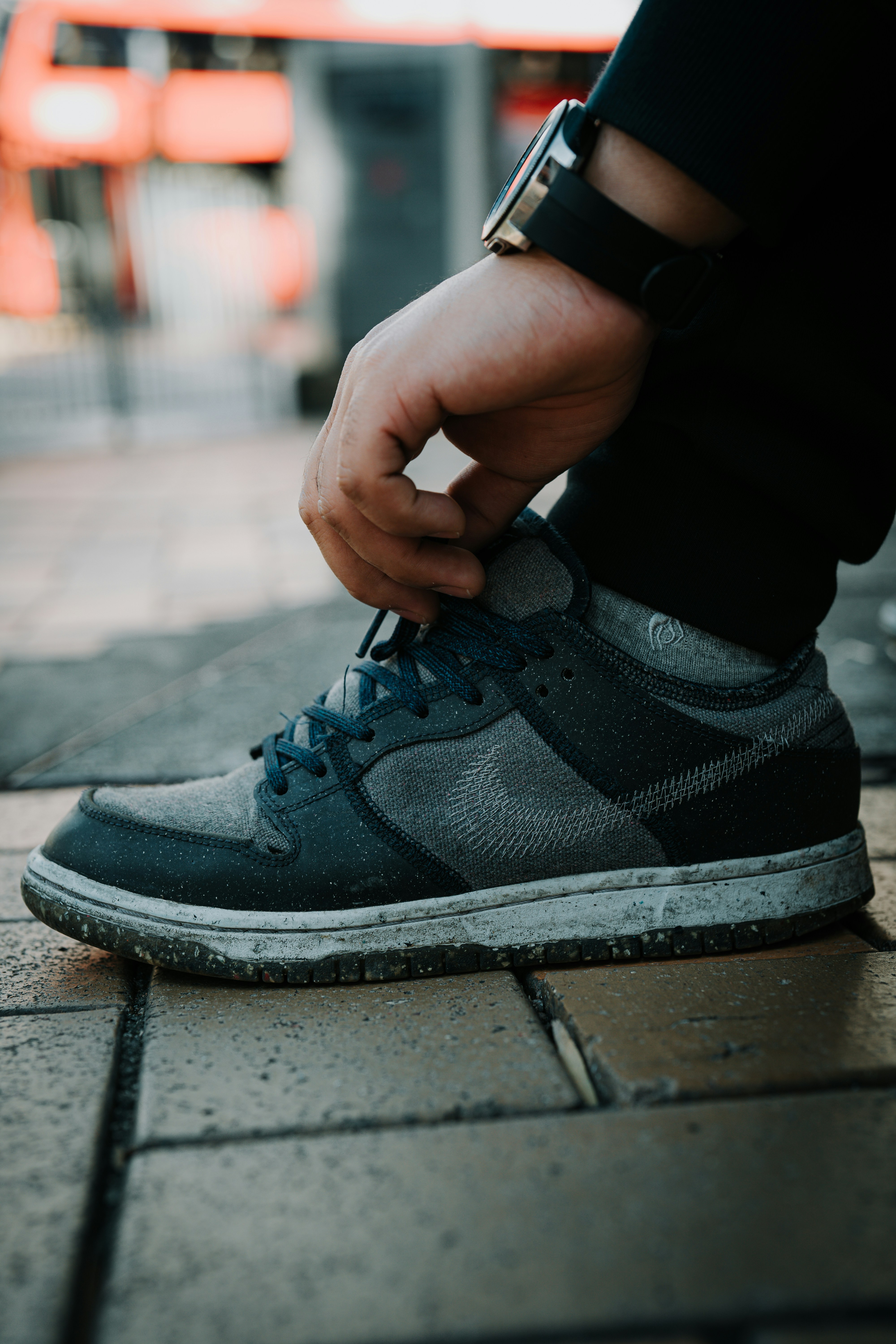 a person tying a shoelace on a sidewalk