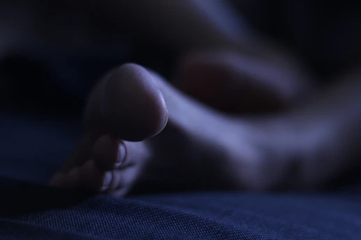 A model capturing artistic foot photos with soft lighting in a cozy room