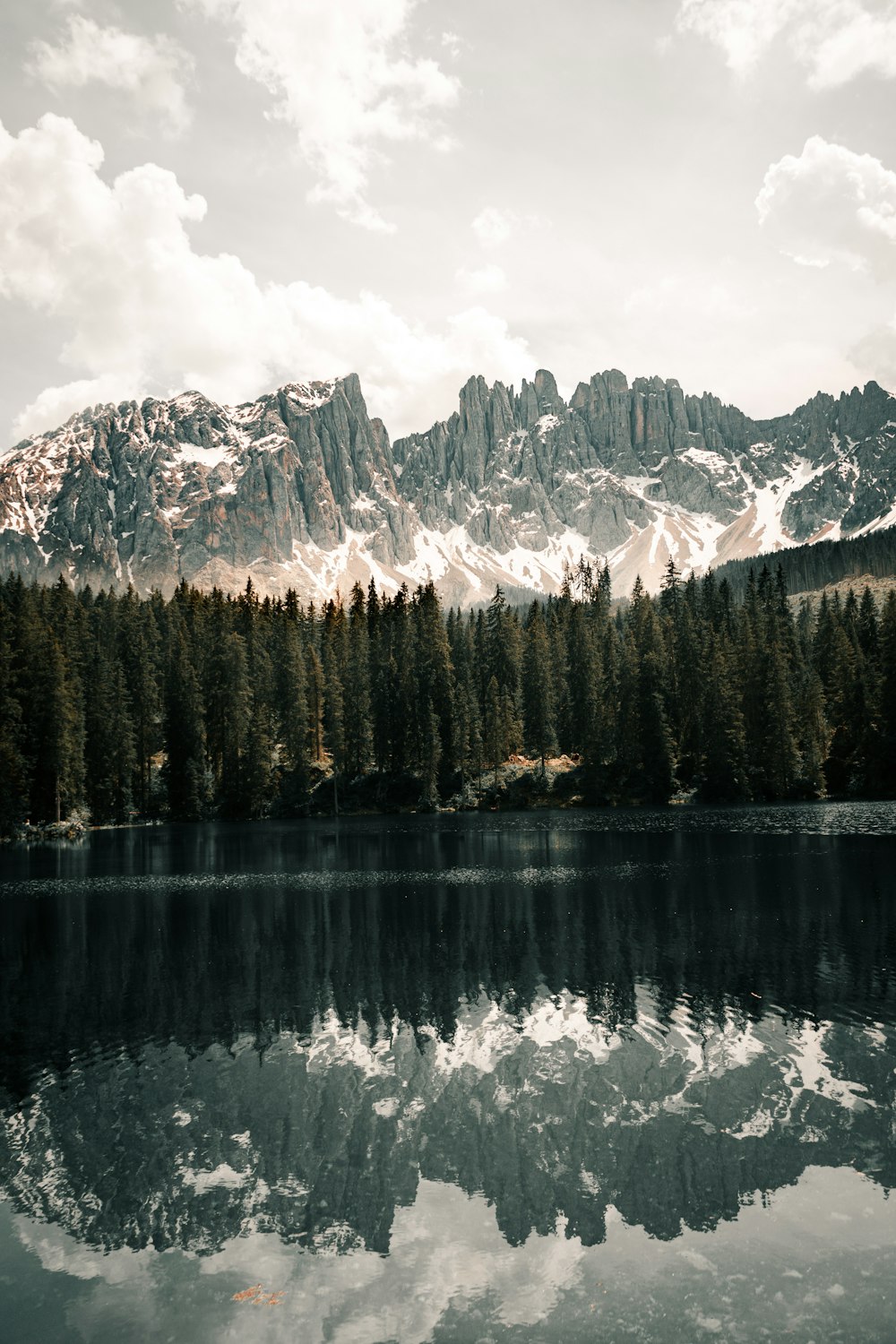 a mountain range is reflected in the still water of a lake