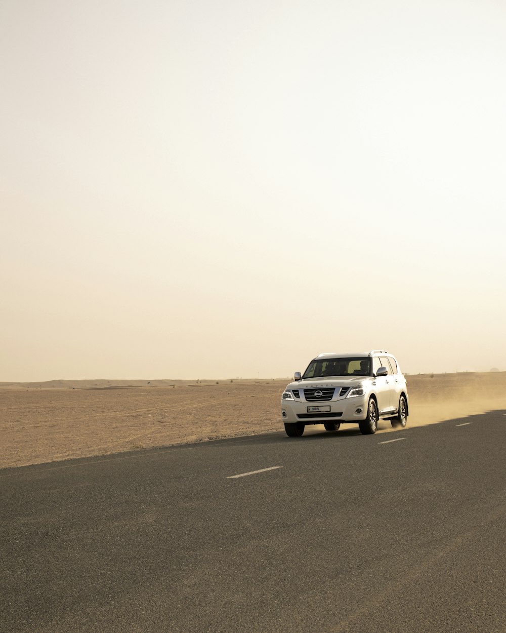 a white suv driving down a desert road