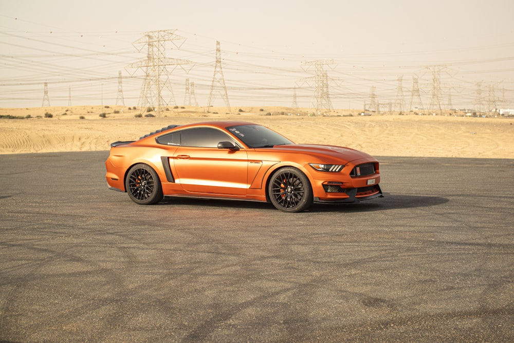 an orange mustang parked in a parking lot