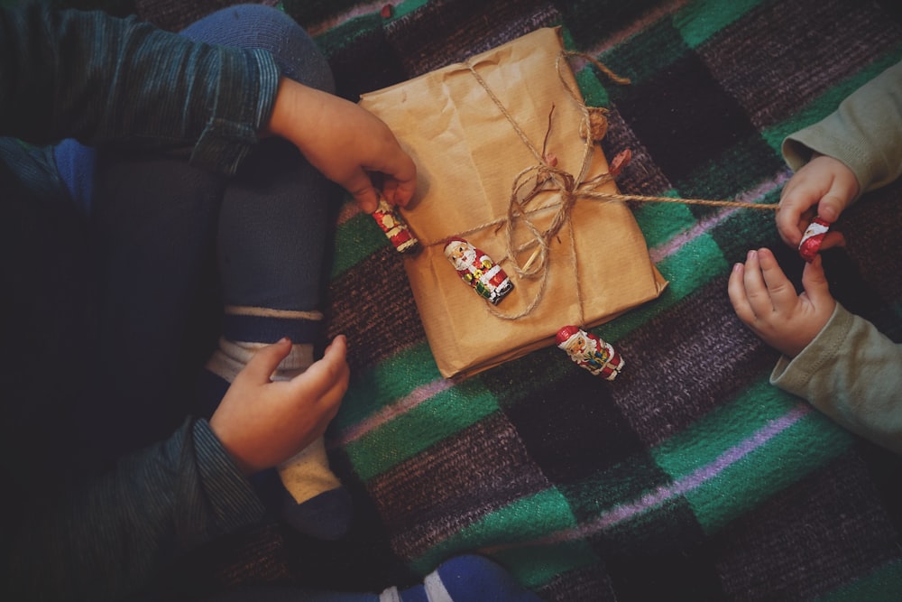 a couple of kids sitting on the floor with a wrapped present
