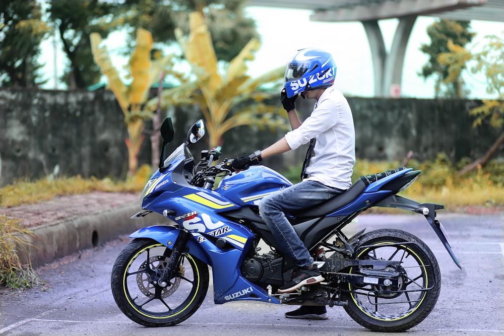 a man riding a blue motorcycle down a street