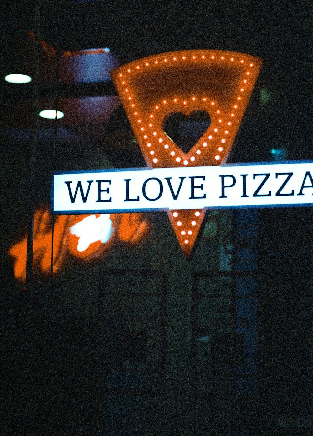 a sign that says we love pizza hanging from the side of a building