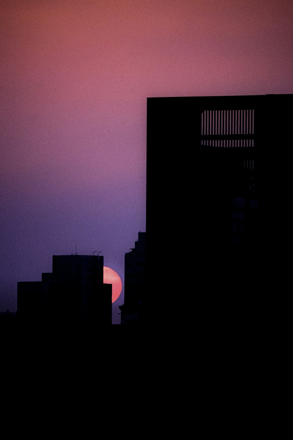 the sun is setting behind a building in the city