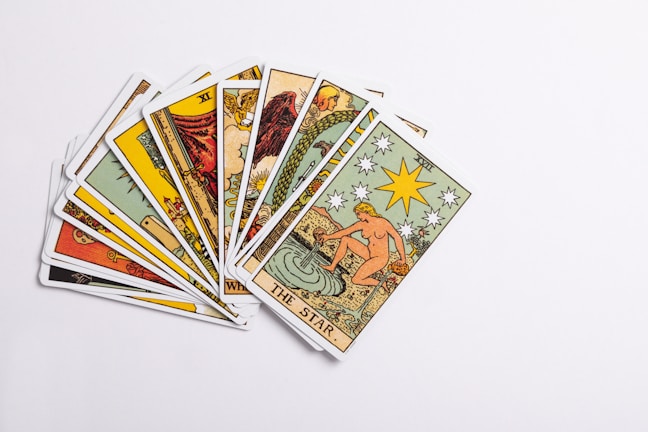 A collection of tarot cards spread out, with the card depicting 'The Star' prominently displayed on top. The cards feature intricate and colorful illustrations with various symbols and figures.