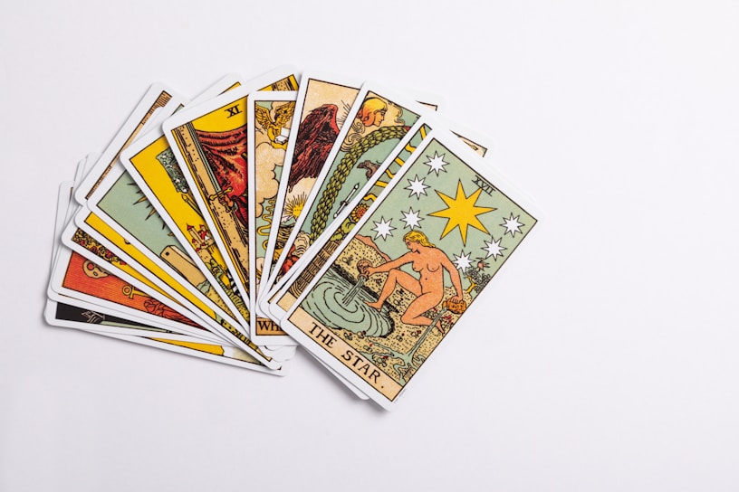 A collection of tarot cards spread out, with the card depicting 'The Star' prominently displayed on top. The cards feature intricate and colorful illustrations with various symbols and figures.