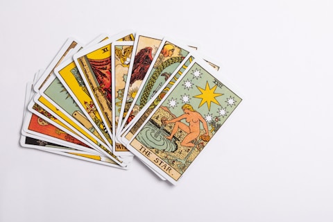 A collection of tarot cards spread out, with the card depicting 'The Star' prominently displayed on top. The cards feature intricate and colorful illustrations with various symbols and figures.