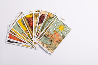 A collection of tarot cards spread out, with the card depicting 'The Star' prominently displayed on top. The cards feature intricate and colorful illustrations with various symbols and figures.