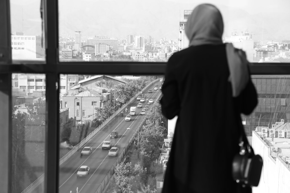 a person looking out a window at a city