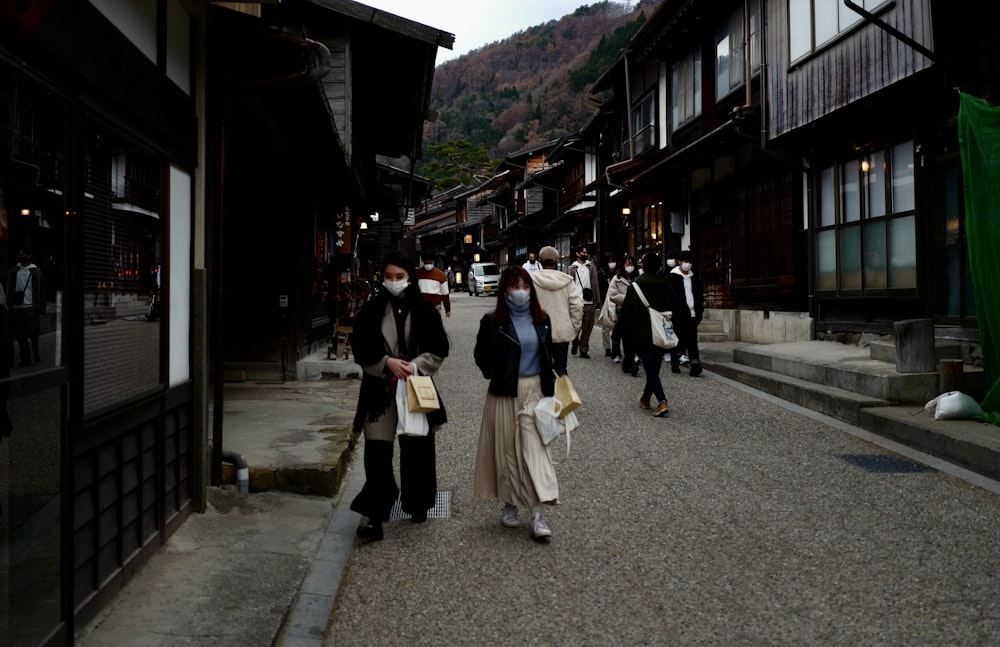 a group of people walking down a street next to tall buildings