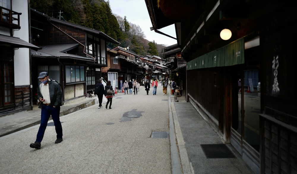 a group of people walking down a street next to tall buildings