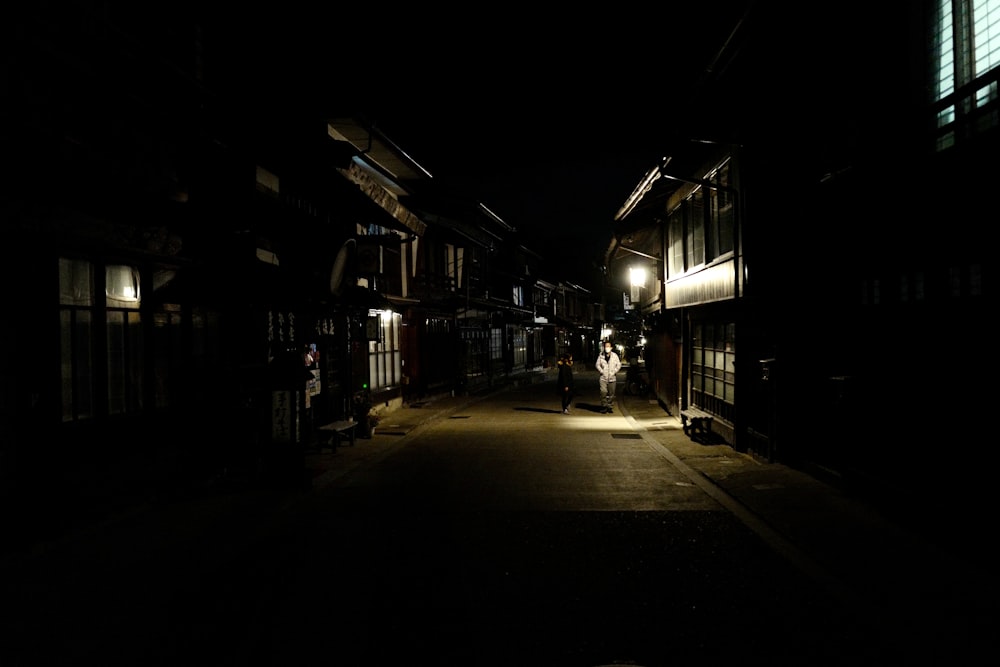 a dark street with a person walking down it at night
