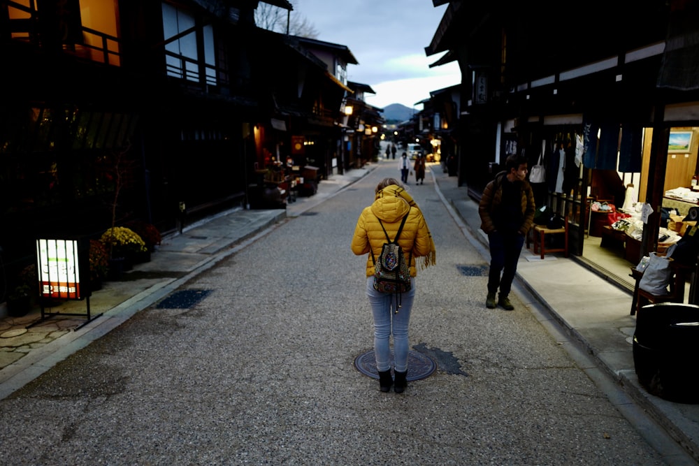 a woman in a yellow jacket walking down a street
