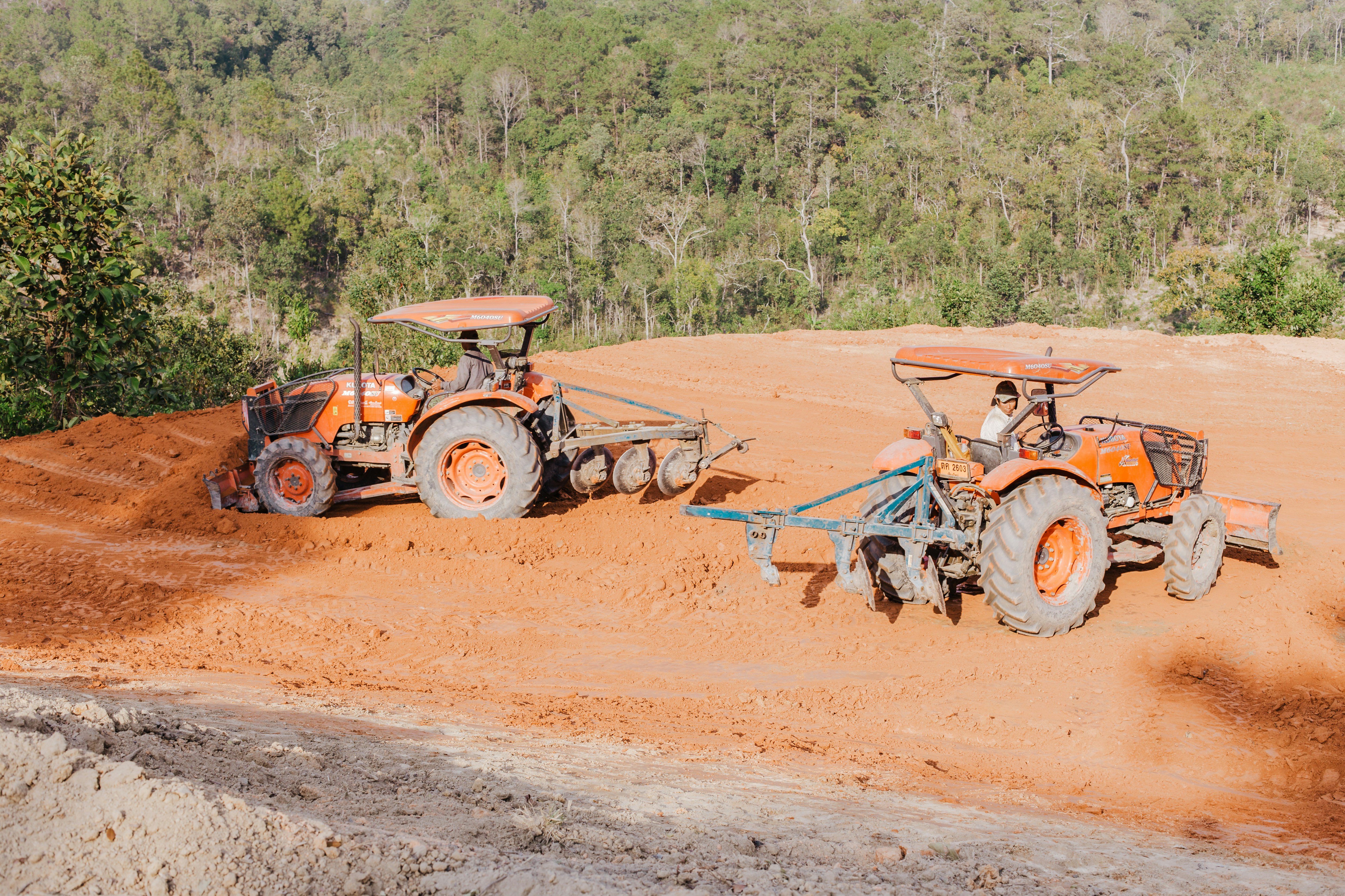 Two tractors are plowing a field in the north of Thailand.