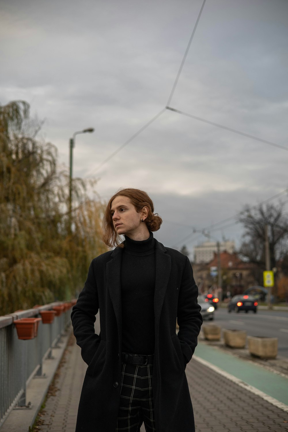 a woman standing on a bridge with her hands in her pockets