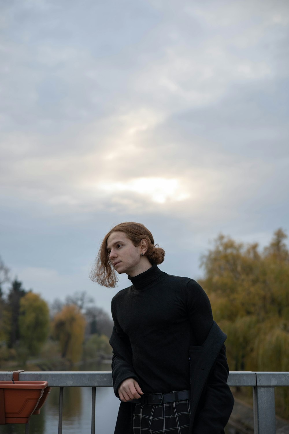 a woman standing on a bridge with her hands in her pockets