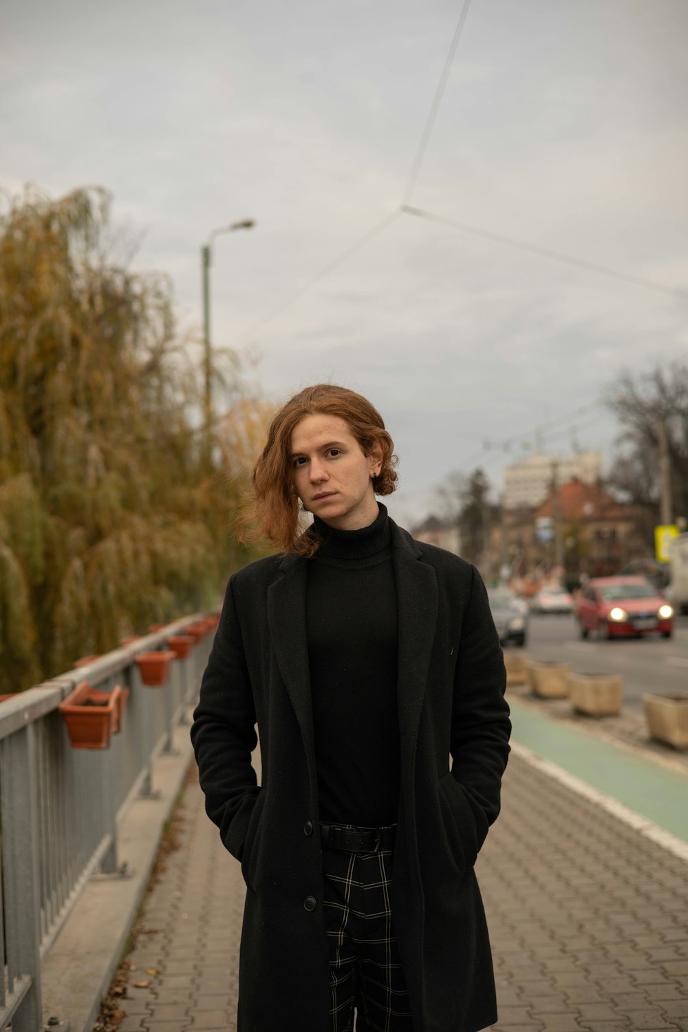 a woman standing on a bridge with her hands in her pockets