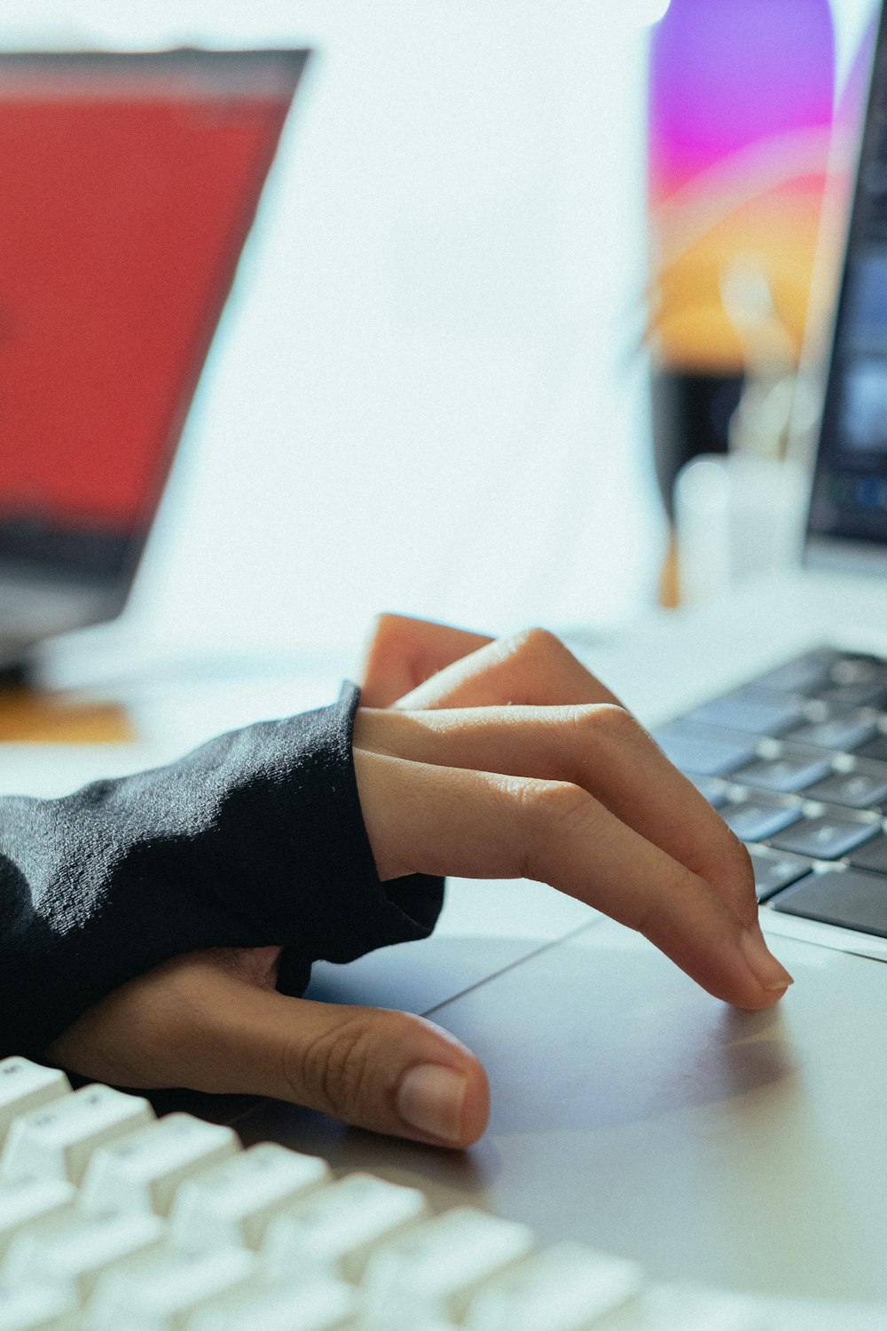 a person's hand on a keyboard with a laptop in the background