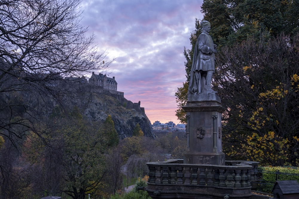 a statue in a park with a castle in the background