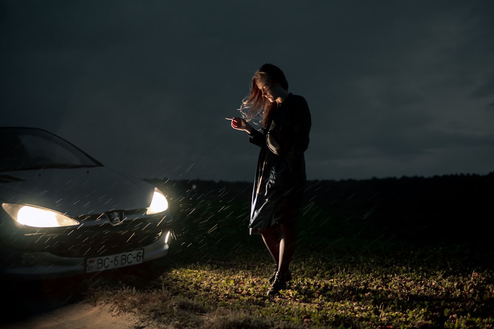 a woman standing next to a car in the rain