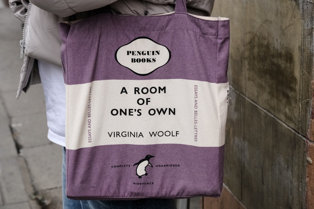 a person holding a bag with a penguin book on it