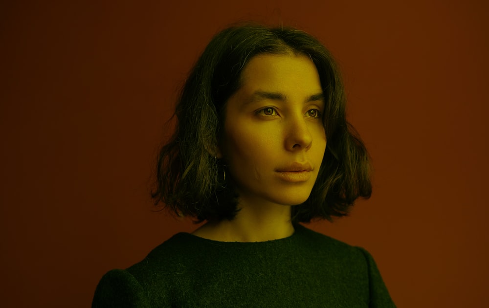 a woman with shoulder length hair standing in front of a red wall