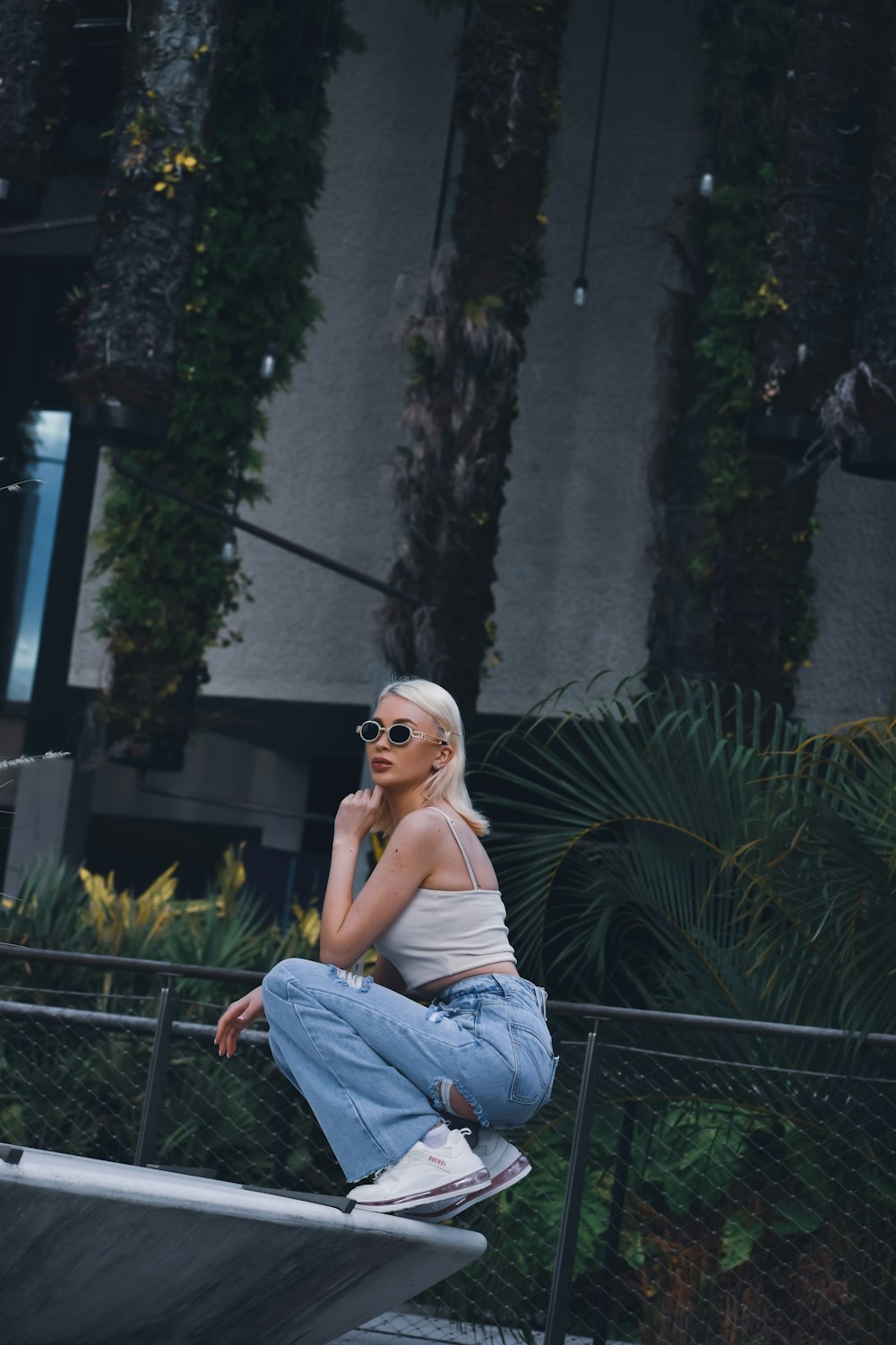 a woman with white hair and sunglasses sitting on a skateboard