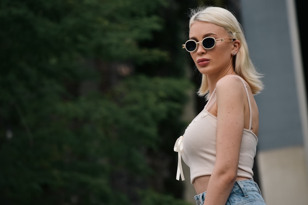 a blonde woman wearing sunglasses and a white top