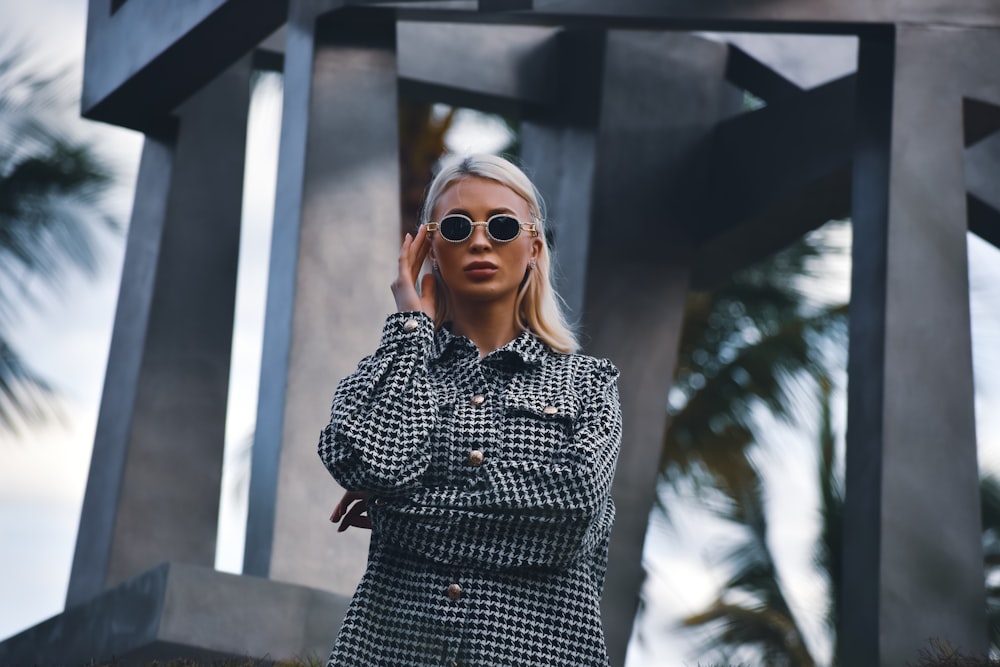 a woman wearing sunglasses standing in front of a sculpture