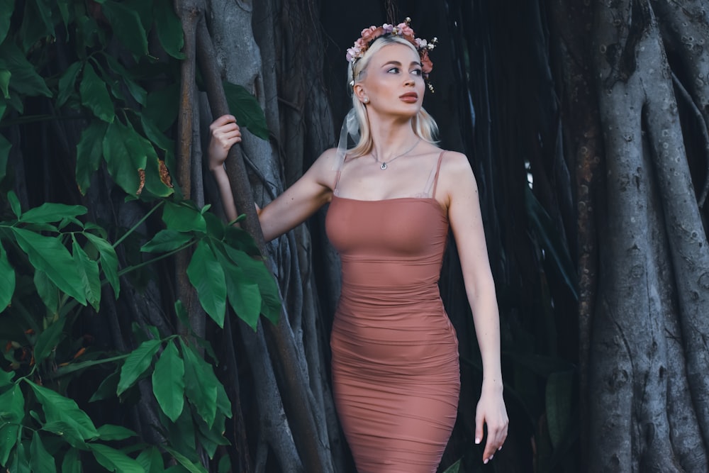 a woman in a dress standing in front of a tree