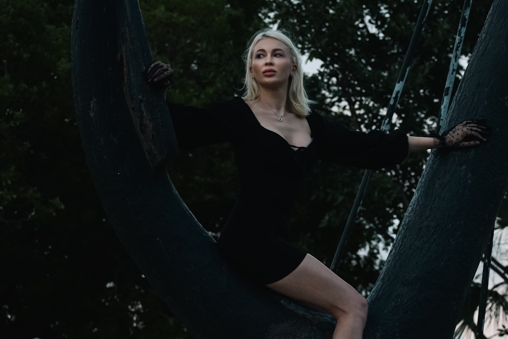 a woman in a black dress sitting on a tree
