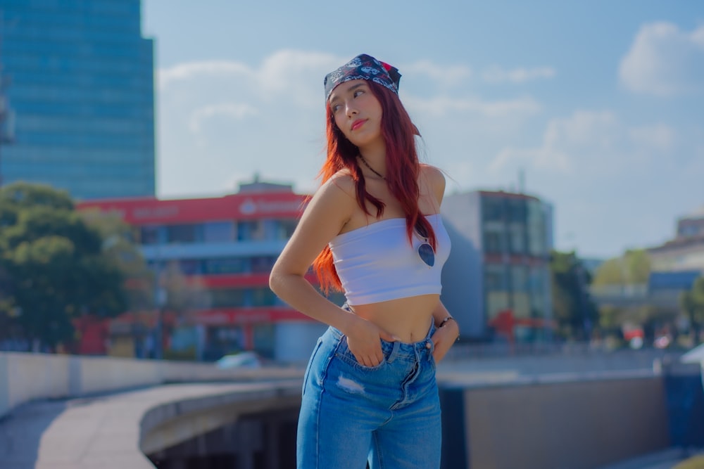 a woman with red hair wearing a white top and blue jeans