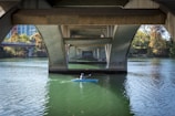 a person in a kayak under a bridge