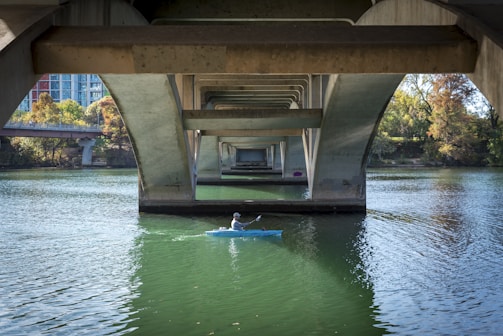 a person in a kayak under a bridge
