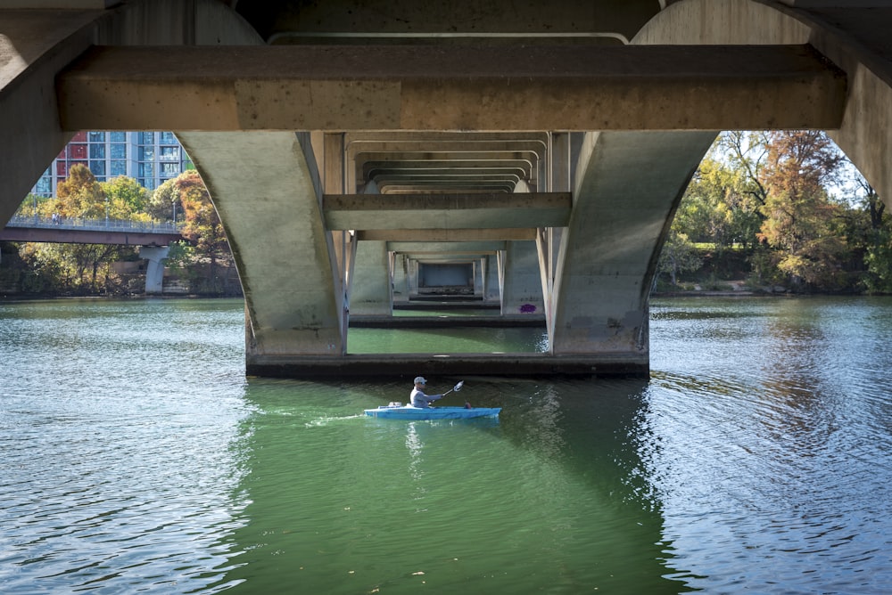 a person in a kayak under a bridge