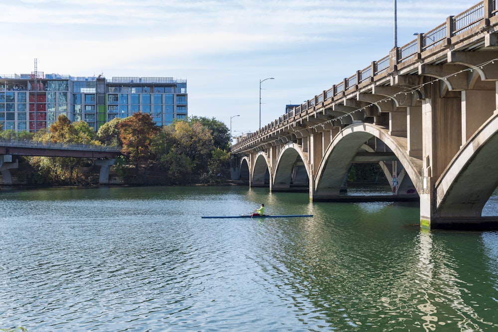 a person rowing a boat under a bridge