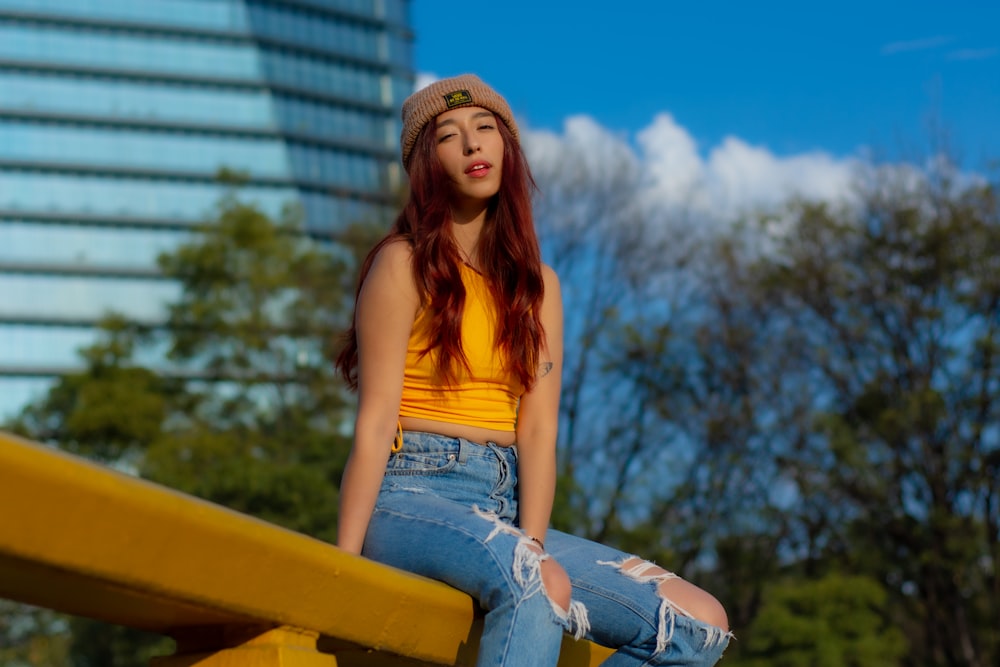 a woman sitting on a yellow bench in front of a tall building