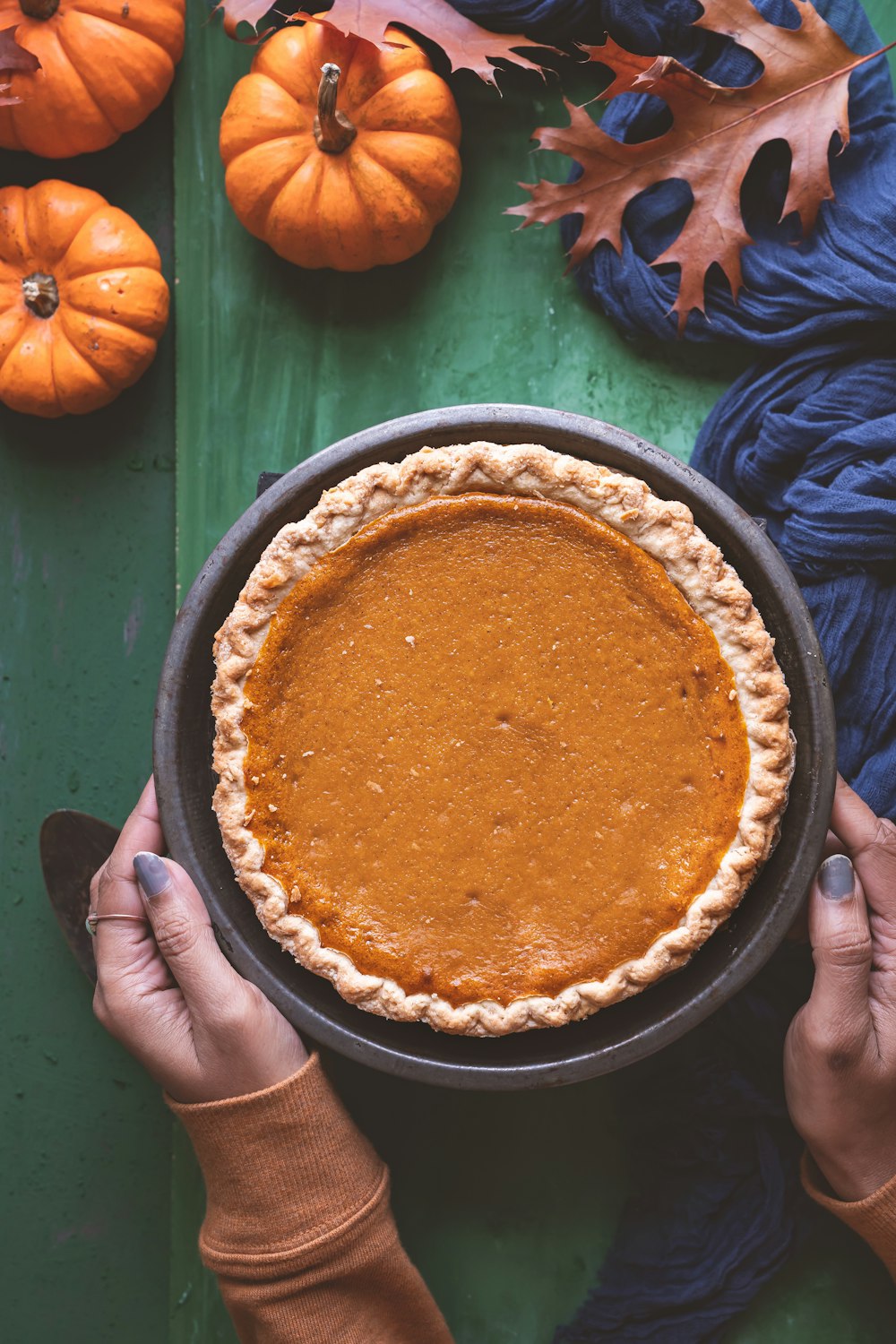 a person holding a pie on top of a green table